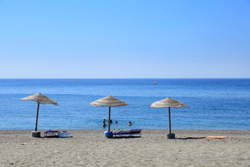 Parasole na tropikalnej plaży i ludzie w morzu na wyspie Rodos w Grecji.