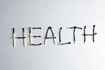 poor health concept health degradation Burnt matches lined with the word health Deterioration of health closeup