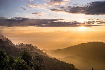 View of sunrise or sunset a valley in a beautiful early morning with fog between hills