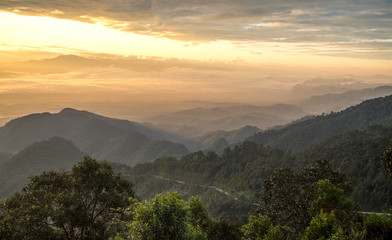 Obraz premium View of a valley in a beautiful early morning with fog between hills
