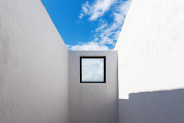 Window and white facade of typical Greek architecture under blue sky. Milos island, Cyclades. Greece.