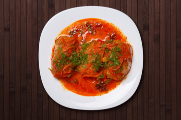 Cabbage rolls in tomato gravy on a white plate. Top view.