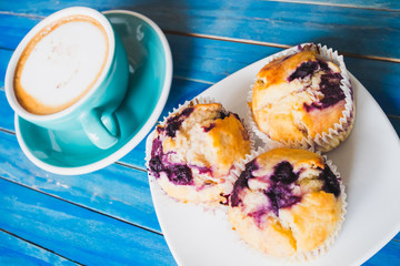 Blueberry cake with hot latte or capucino coffee in  blue club on blue vintage wooden table background