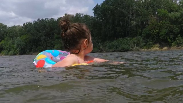 Little girl learns to swim. Child in an inflatable circle.