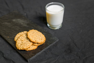 Peanut butter oatmeal cookies with milk against black background