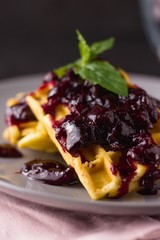 Pile of waffles with cherry jam and mint leaves. Selective focus and low depth of field, preserve in focus