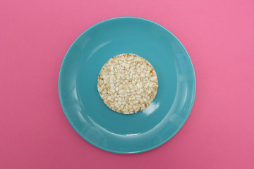 Vegetarian rice bread on a blue plate on a pink background, top view. Diet.