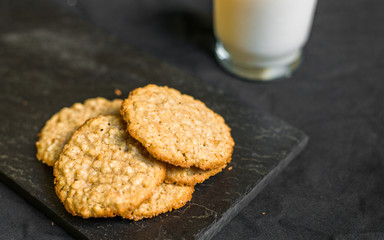 Peanut butter oatmeal cookies with milk against black background