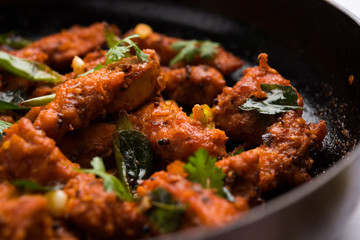 Chicken 65 - spicy deep fried Bar appetizer or quick snack from India in a frying pan over white...