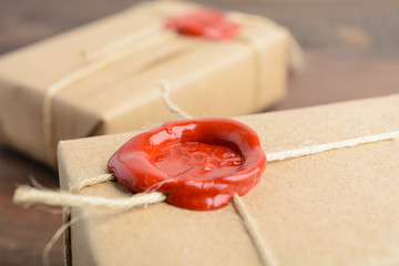 Gifts in craft paper with sealing wax over brown wooden table