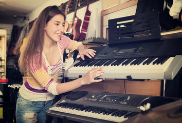 Happy young girl choosing synthesizer