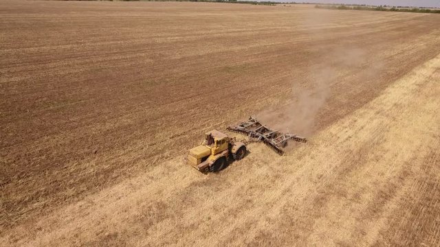 Amazing aerial shot of a big tractor drawing a spike and a disc harrows to remove wheat straw and to do a  tillage in Eastern Europe in a sunny day in autumn. The landscape looks great