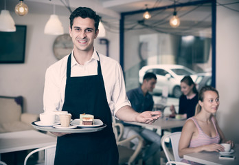 Portrait of cheerful waiter inviting to coffee