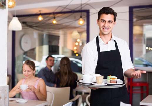 Smiling waiter is warmly welcoming guests