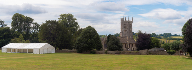 Fototapeta na wymiar Newton St. Philip church and village green. Idyllic English village with ancient church of St. Philip and St. James and cricket pitch, Somerset, UK