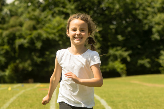 Girl running at School Sports Day. Young child sprinting hard and happily during summer traditional school event