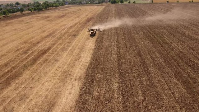 Impressive aerial shot of a big tractor drawing a spike and a disc harrows to remove wheat straw and to do a  tillage in Eastern Europe in a sunny day in autumn. The landscape looks great