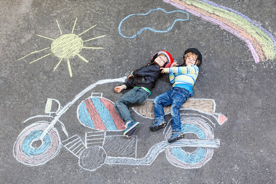 Two kid boys in helmet with motorcycle picture drawing with colo