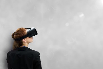 Woman in VR headset looking up against grey background