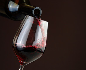 Fototapeta na wymiar Pouring red wine on dark background
