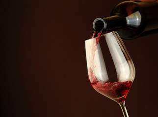 Naklejka na ściany i meble Red wine pouring into a glass