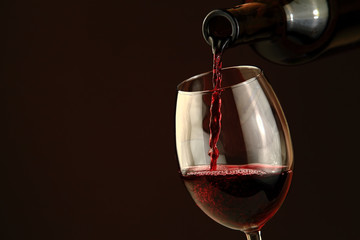 Naklejka na ściany i meble Red wine pouring into a wine glass