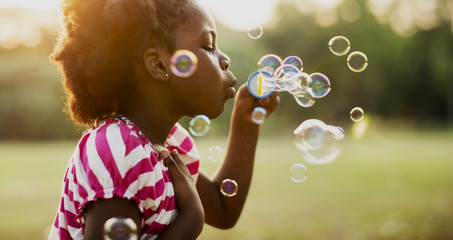 Children is playing bubbles in a park - Powered by Adobe