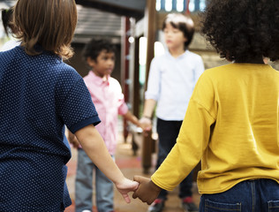 Group of diverse kindergarten students standing holding hands together