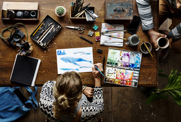 Aerial view of woman drawing with water color on paper