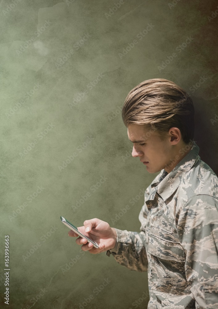 Canvas Prints Soldier man looking at a phone against green background