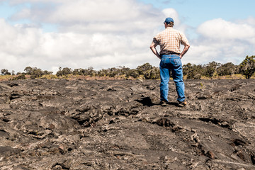 Fototapeta premium A man is standing on lava land at the Island of Hawaii
