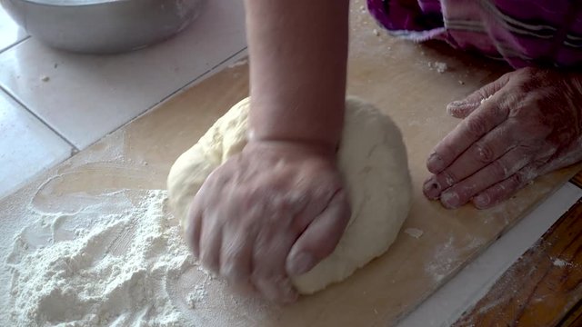 Top view shot of female hands mixing dough. Female hands knead dough on wooden board. 4k prores footage