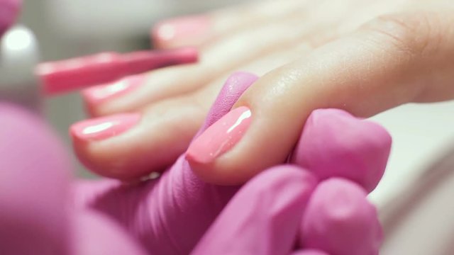 Professional manicure closeup footage. Gel polish on the nails. Female master in the salon makes a spa procedure for the fingernails of the client. Beauty industry, relax concept.