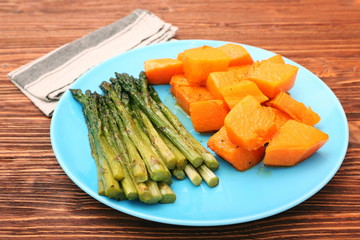 Baked asparagus pumpkin on plate on wooden background
