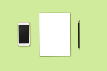Modern workplace with smartphone, blank paper and pencil copy space on green background. Top view. Flat lay style.