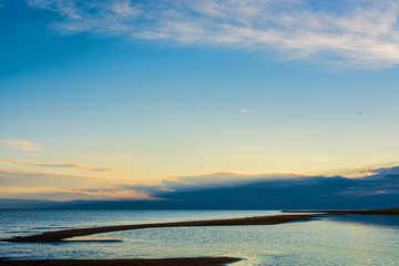 Obraz premium rippled surface of cold lake under sky with fluffy clouds at sunrise 