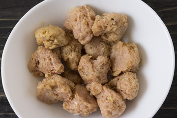 Soy meat in a white bowl on a wooden table. Replacement of meat.
