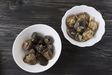 Marinated mushrooms in a white bowl on a wooden table