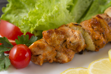 Chicken skewers with vegetables on a white plate. Still life in rustic style. Dish on a wooden table.