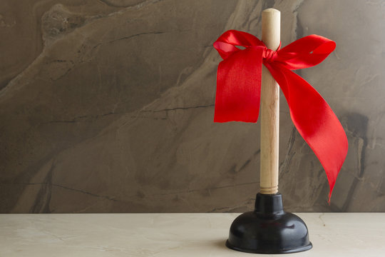 Plunger with red bow. Repair of plumbing.