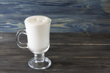 A glass with an eggnog on a wooden table