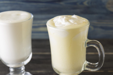 Two glasses of eggnog on a wooden table. Christmas time.