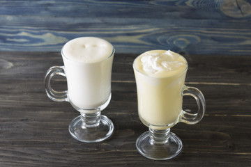 Two glasses of eggnog on a wooden table. Christmas time.
