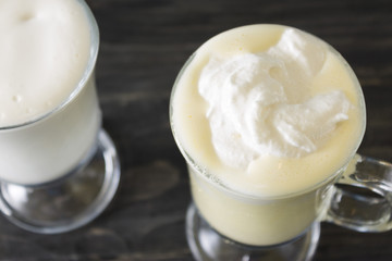 Two glasses of eggnog on a wooden table. Christmas time.