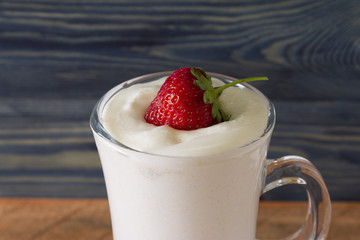 A glass with an eggnog on a wooden table