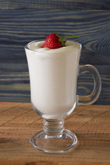 A glass with an eggnog on a wooden table