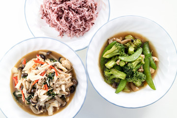 homemade stir-fried vegetable combination and stir-fried crab and mushroom combination with cooked brown rice on white background