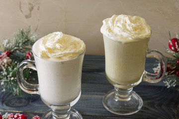 Two glasses of eggnog on a wooden table. Christmas time.