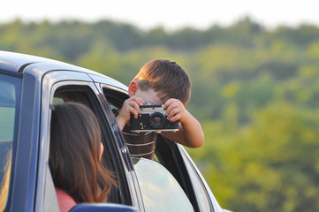 Boy Taking photo of his mom on start of journey. Travel concept. Happy family in the car.