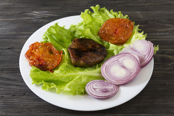 Fried meat with vegetables on a white plate. Tasty and nutritious dish.